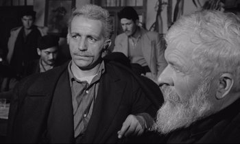 Movie still from “Zorba the Greek” (1964), directed by Michael Cacoyannis – A man in a suit and a man with a beard; Medium shot, Over the shoulder angle