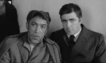 Movie still from “Zorba the Greek” (1964), directed by Michael Cacoyannis – A black - and - white photo of two men standing next to each other; Medium shot, High angle