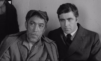 Movie still from “Zorba the Greek” (1964), directed by Michael Cacoyannis – A black - and - white photo of two men standing next to each other; Medium shot, High angle