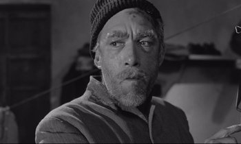 Movie still from “Zorba the Greek” (1964), directed by Michael Cacoyannis – A black and white photo of a man with a hat on; Close Up shot, Low angle