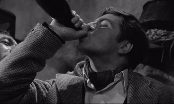 Movie still from “Zorba the Greek” (1964), directed by Michael Cacoyannis – A man drinking a bottle of wine from a wine bottle; Close Up shot, Overhead angle