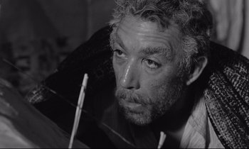 Movie still from “Zorba the Greek” (1964), directed by Michael Cacoyannis – Black and white photograph of a man looking out a window; Close Up shot, Low angle