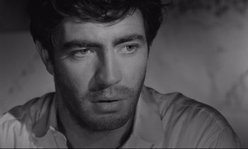 Movie still from “Zorba the Greek” (1964), directed by Michael Cacoyannis – Black and white photograph of a man looking at the camera; Close Up shot, Low angle