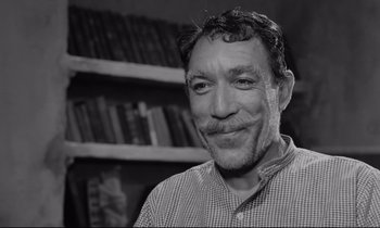 Movie still from “Zorba the Greek” (1964), directed by Michael Cacoyannis – Black and white photograph of a man smiling for the camera; Close Up shot, Low angle