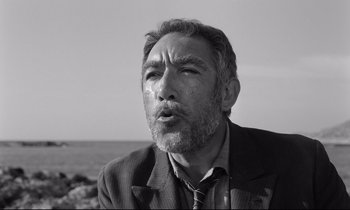 Movie still from “Zorba the Greek” (1964), directed by Michael Cacoyannis – Black and white photograph of a man with a beard; Close Up shot, Low angle
