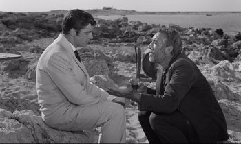 Movie still from “Zorba the Greek” (1964), directed by Michael Cacoyannis – Two men sitting on a rock on the beach; Medium shot, Over the shoulder angle