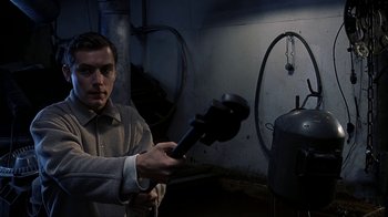 Movie still from “eXistenZ” (1999), directed by David Cronenberg – A man holding a blow dryer in a room; Medium shot, High angle