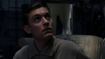 Movie still from “eXistenZ” (1999), directed by David Cronenberg – A man looking up into the air while sitting on a couch; Close Up shot, Low angle