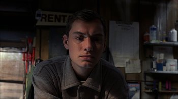 Movie still from “eXistenZ” (1999), directed by David Cronenberg – A young man is sitting in a dark room; Close Up shot, Low angle
