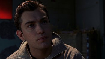 Movie still from “eXistenZ” (1999), directed by David Cronenberg – A young man looking into the distance in the dark; Close Up shot, Over the shoulder angle