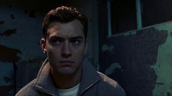 Movie still from “eXistenZ” (1999), directed by David Cronenberg – A young man in a gray jacket looking at the camera; Close Up shot, Low angle