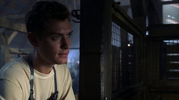Movie still from “eXistenZ” (1999), directed by David Cronenberg – A man sitting in front of a fence looking into the distance; Close Up shot, Low angle