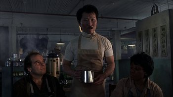 Movie still from “eXistenZ” (1999), directed by David Cronenberg – A man in an apron holding a metal container; Medium shot, Low angle