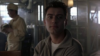 Movie still from “eXistenZ” (1999), directed by David Cronenberg – A young man in a brown jacket is looking at the camera; Close Up shot, Over the shoulder angle