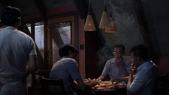 Movie still from “eXistenZ” (1999), directed by David Cronenberg – A group of people sitting at a table eating food; Medium shot, High angle