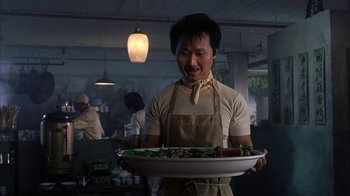 Movie still from “eXistenZ” (1999), directed by David Cronenberg – A man in an apron holding a tray of food; Medium shot, Low angle