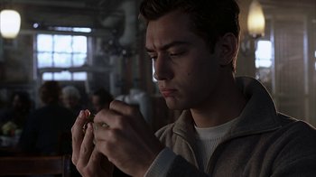 Movie still from “eXistenZ” (1999), directed by David Cronenberg – A man holding a cigarette in his hands; Close Up shot, Low angle