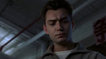 Movie still from “eXistenZ” (1999), directed by David Cronenberg – A young man is looking at the camera; Close Up shot, Low angle