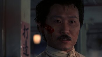 Movie still from “eXistenZ” (1999), directed by David Cronenberg – A person with blood on his face; Close Up shot, Over the shoulder angle