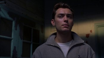Movie still from “eXistenZ” (1999), directed by David Cronenberg – A man in a gray jacket is looking at the camera; Close Up shot, Low angle