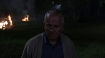 Movie still from “eXistenZ” (1999), directed by David Cronenberg – An older man in a blue shirt and a brown jacket; Close Up shot, Over the shoulder angle