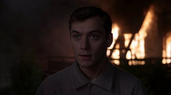Movie still from “eXistenZ” (1999), directed by David Cronenberg – A young man stares into the distance in front of a fireplace; Close Up shot, Over the shoulder angle