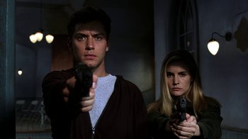 Movie still from “eXistenZ” (1999), directed by David Cronenberg – A man and a woman holding guns in a dark room; Close Up shot, Low angle
