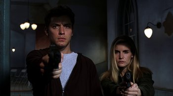 Movie still from “eXistenZ” (1999), directed by David Cronenberg – A man and a woman holding guns in a dark room; Close Up shot, Low angle