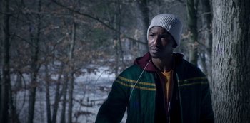Movie still from “Archive 81” (2022), created by Rebecca Sonnenshine – A man in a white hat and a green and yellow jacket; Close Up shot, Over the shoulder angle