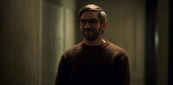Movie still from “Archive 81” (2022), created by Rebecca Sonnenshine – A man with a beard wearing glasses and a sweater; Close Up shot, Over the shoulder angle