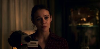 Movie still from “Archive 81” (2022), created by Rebecca Sonnenshine – A woman looking into a mirror while holding a video camera; Close Up shot, Over the shoulder angle