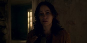 Movie still from “Archive 81” (2022), created by Rebecca Sonnenshine – A woman in a dark room holding a tie; Close Up shot, Over the shoulder angle