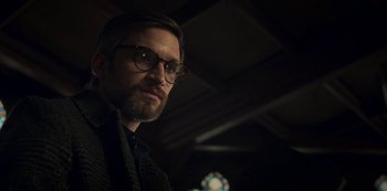 Movie still from “Archive 81” (2022), created by Rebecca Sonnenshine – A person wearing glasses and a jacket; Close Up shot, Low angle