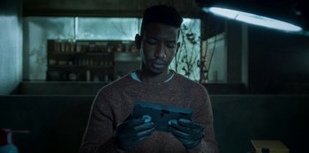 Movie still from “Archive 81” (2022), created by Rebecca Sonnenshine – A man holding a piece of metal in his hands; Close Up shot, Over the shoulder angle