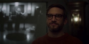 Movie still from “Archive 81” (2022), created by Rebecca Sonnenshine – A man with a beard wearing glasses looking at the camera; Close Up shot, Over the shoulder angle