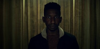 Movie still from “Archive 81” (2022), created by Rebecca Sonnenshine – A man with a beard is wearing a jacket; Close Up shot, Low angle