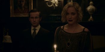 Movie still from “Archive 81” (2022), created by Rebecca Sonnenshine – A man and a woman standing next to each other holding a lit candle; Medium shot, Low angle