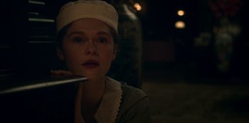 Movie still from “Archive 81” (2022), created by Rebecca Sonnenshine – A young woman in a white hat is sitting in a dimly - lit room; Close Up shot, Over the shoulder angle