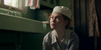 Movie still from “Archive 81” (2022), created by Rebecca Sonnenshine – A woman wearing a white hat looking up at the sky; Close Up shot, High angle