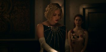 Movie still from “Archive 81” (2022), created by Rebecca Sonnenshine – A woman in a black dress and white gloves; Medium shot, Low angle