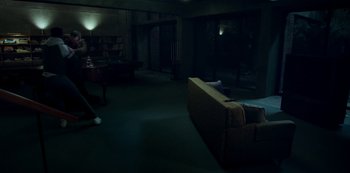 Movie still from “Archive 81” (2022), created by Rebecca Sonnenshine – A living room with a couch and a table in it; Wide shot, High angle
