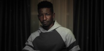 Movie still from “Archive 81” (2022), created by Rebecca Sonnenshine – A young man in a gray and white hoodie; Close Up shot, Low angle