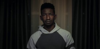 Movie still from “Archive 81” (2022), created by Rebecca Sonnenshine – A man in a gray and white hoodie is looking at the camera; Close Up shot, Low angle