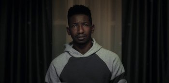 Movie still from “Archive 81” (2022), created by Rebecca Sonnenshine – A man in a gray and white hoodie is looking at the camera; Close Up shot, Low angle
