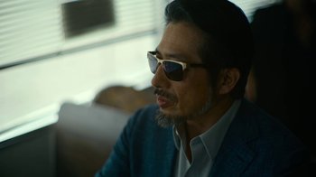 Movie still from “Army of the Dead” (2021), directed by Zack Snyder – A person wearing a suit and sunglasses; Close Up shot, Low angle