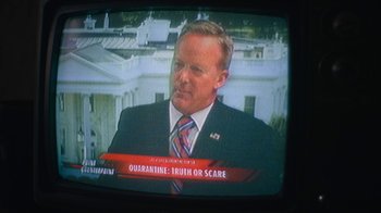 Movie still from “Army of the Dead” (2021), directed by Zack Snyder – A man in a suit and tie sitting in front of a tv; Medium shot, High angle