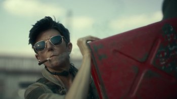 Movie still from “Army of the Dead” (2021), directed by Zack Snyder – A man in sunglasses smoking a cigarette while holding a red bag; Medium shot, Over the shoulder angle