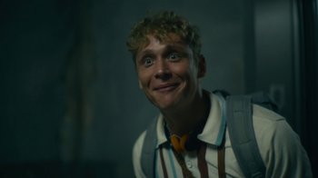 Movie still from “Army of the Dead” (2021), directed by Zack Snyder – A young man with blonde curly hair wearing a tie; Close Up shot, Low angle