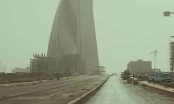 Movie still from “Atlantics” (2019), directed by Mati Diop – A road with a tall building in the background; Extreme Wide shot, Low angle