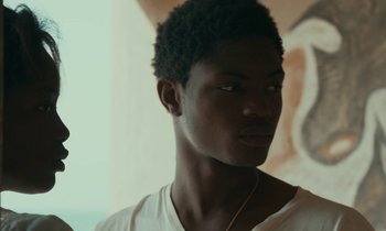 Movie still from “Atlantics” (2019), directed by Mati Diop – A young man with a beard is wearing a white shirt; Close Up shot, Low angle